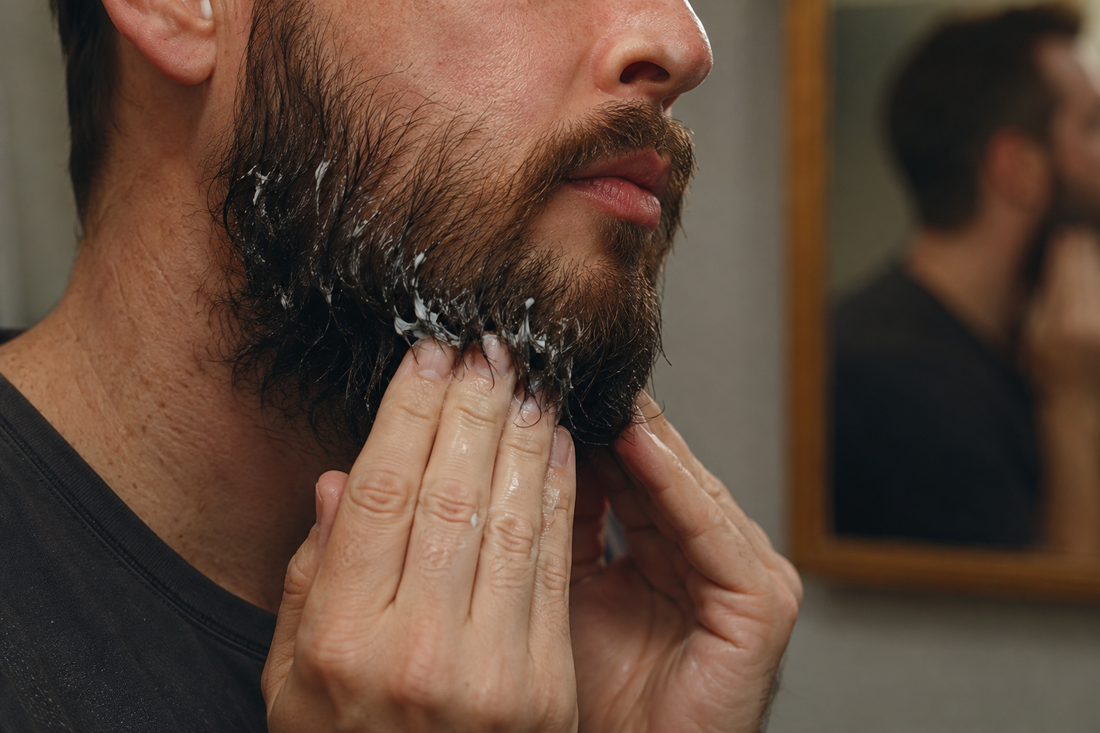 Man working a rinse-out treatment mask into a damp beard with his fingertips
