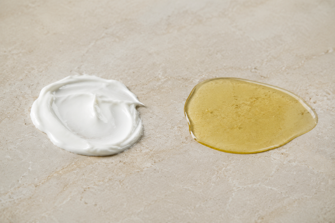 A swirl of white cream beside a pool of golden oil on pale stone