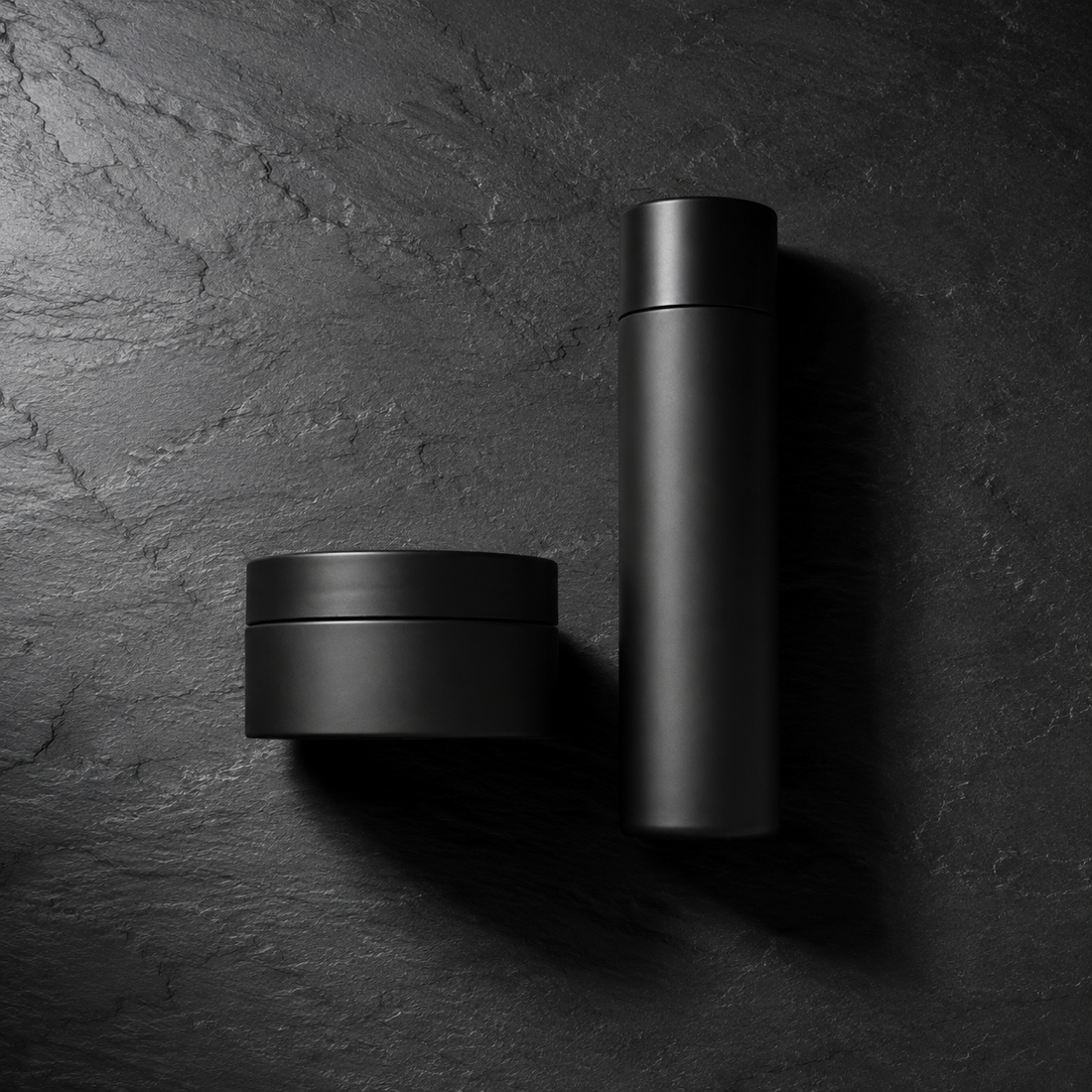A wide jar and a slim bottle side by side on dark slate, the two beard conditioner formats