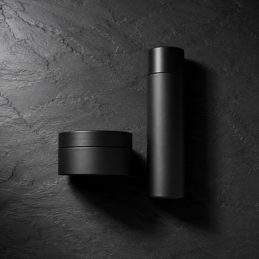 A wide jar and a slim bottle side by side on dark slate, the two beard conditioner formats