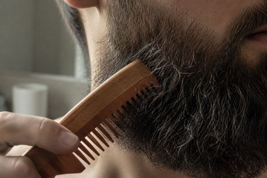 Wooden comb moving through a coarse dark beard in natural light